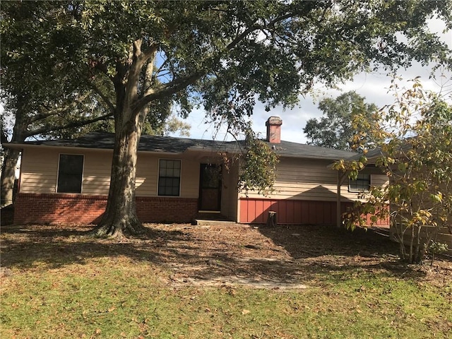 rear view of property with brick siding, a chimney, and a yard