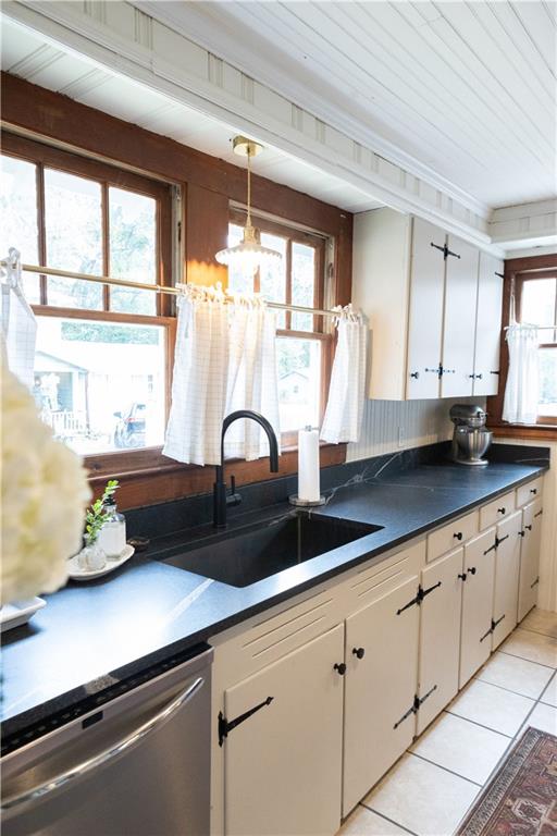 kitchen with sink, dishwasher, white cabinetry, light tile patterned flooring, and decorative light fixtures