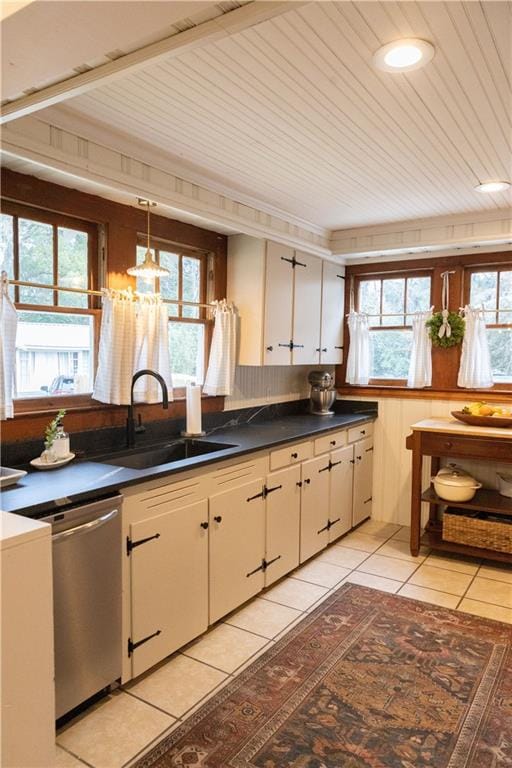 kitchen featuring dishwasher, sink, white cabinets, hanging light fixtures, and light tile patterned floors