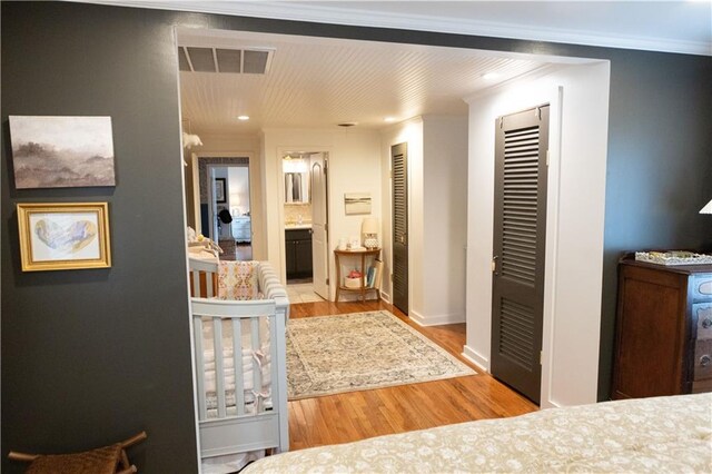 hallway featuring crown molding and light hardwood / wood-style floors