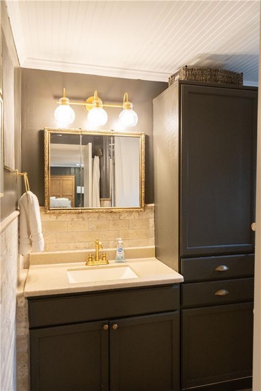 bathroom with crown molding, vanity, and backsplash