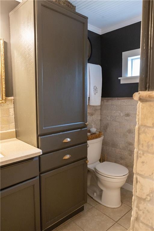 bathroom with tile patterned flooring, tile walls, vanity, ornamental molding, and toilet