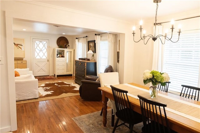 dining space featuring crown molding, hardwood / wood-style floors, and an inviting chandelier