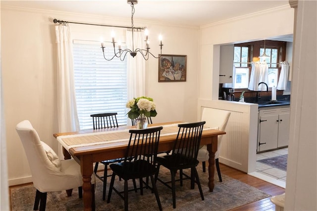 dining area with a notable chandelier, crown molding, wood-type flooring, and sink