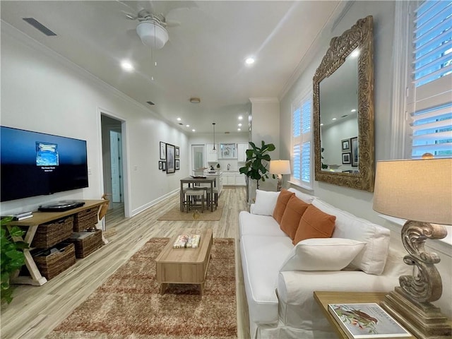 living room featuring ceiling fan, ornamental molding, and light hardwood / wood-style flooring