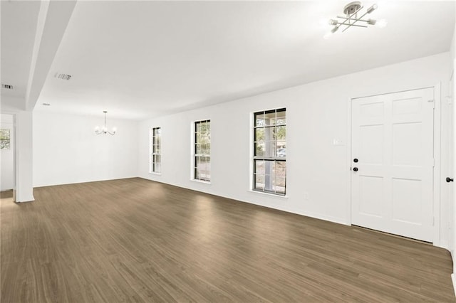 unfurnished living room with an inviting chandelier and dark hardwood / wood-style floors