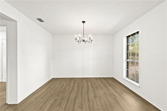 unfurnished room featuring hardwood / wood-style flooring, a wealth of natural light, and a chandelier