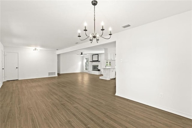 unfurnished living room featuring ceiling fan with notable chandelier and dark wood-type flooring