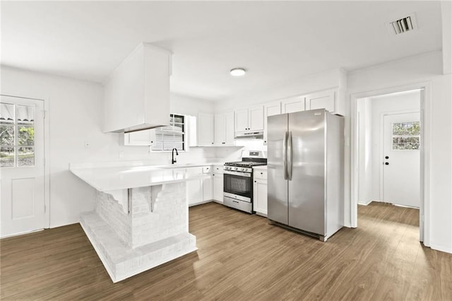 kitchen with white cabinetry, a wealth of natural light, a breakfast bar, and appliances with stainless steel finishes