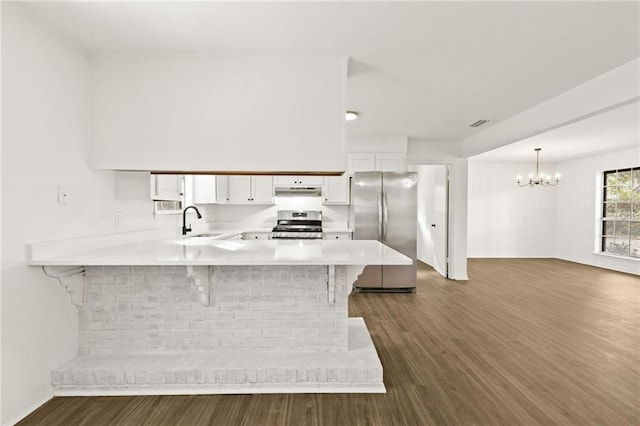 kitchen featuring a kitchen breakfast bar, appliances with stainless steel finishes, kitchen peninsula, dark hardwood / wood-style floors, and white cabinets