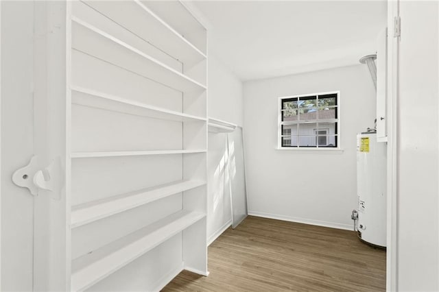 spacious closet with water heater and wood-type flooring