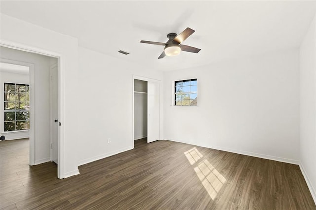 unfurnished bedroom featuring ceiling fan, dark wood-type flooring, and a closet