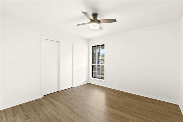 unfurnished bedroom with ceiling fan, dark wood-type flooring, and a closet