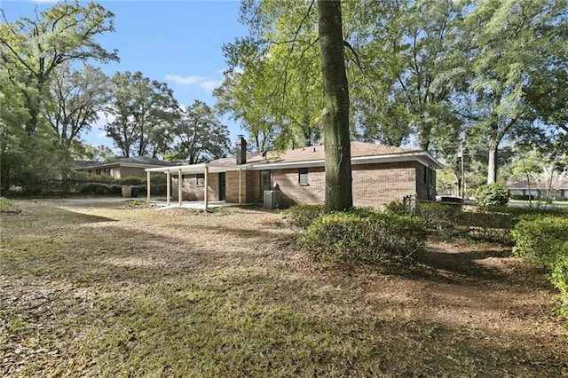 rear view of property featuring a lawn and cooling unit