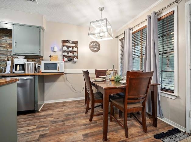 dining space with dark hardwood / wood-style floors, a textured ceiling, an inviting chandelier, and ornamental molding