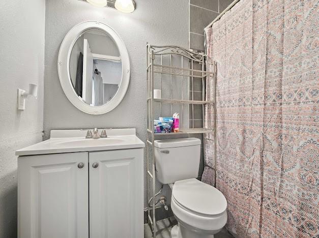 bathroom with curtained shower, vanity, and toilet