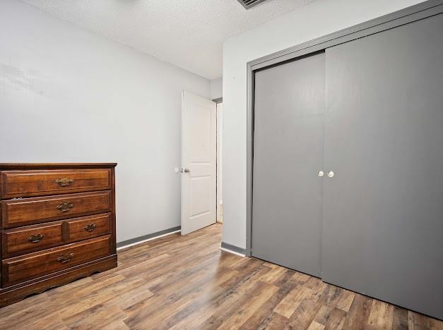 unfurnished bedroom with a textured ceiling, a closet, and light hardwood / wood-style flooring