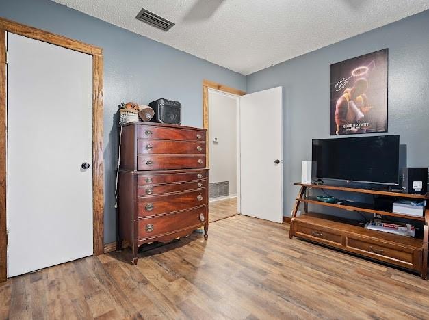 interior space featuring ceiling fan, a textured ceiling, and light hardwood / wood-style floors