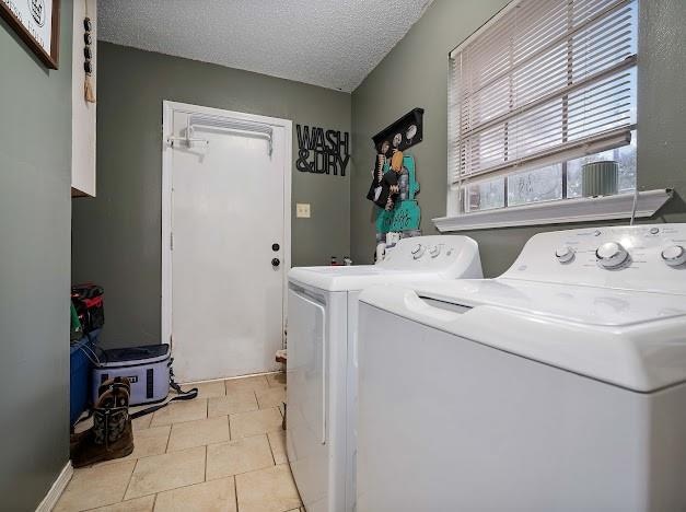 clothes washing area featuring washing machine and clothes dryer, light tile patterned floors, and a textured ceiling