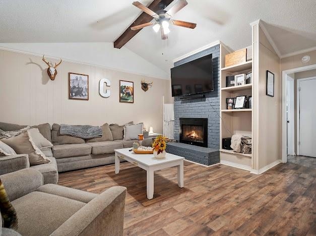 living room featuring a brick fireplace, hardwood / wood-style floors, ceiling fan, lofted ceiling with beams, and built in features