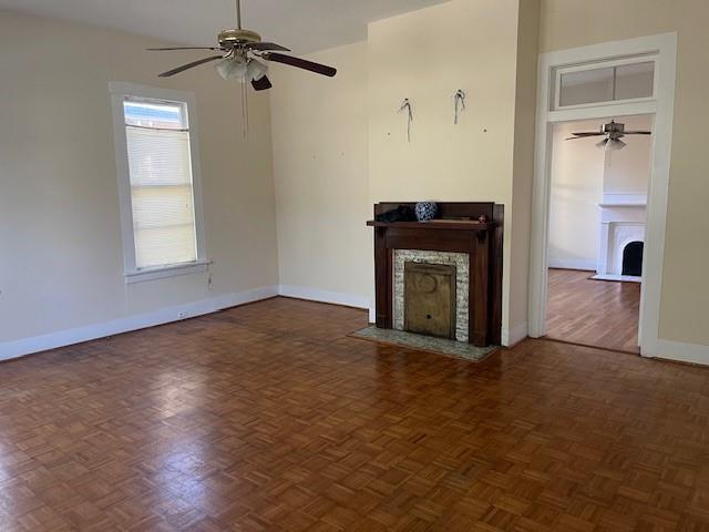 unfurnished living room featuring a fireplace with flush hearth, a ceiling fan, and baseboards