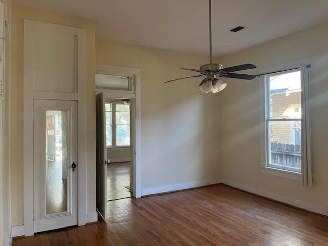 spare room with dark wood finished floors, baseboards, visible vents, and ceiling fan