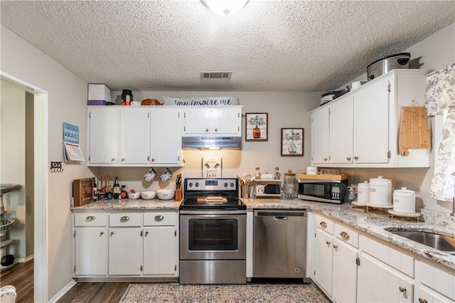 6250 Vivian Broadus Rd, Eight Mile, AL 36613 - kitchen with stainless steel appliances, under cabinet range hood, a textured ceiling, white cabinetry, and wood finished floors