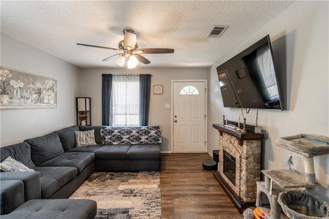 6250 Vivian Broadus Rd, Eight Mile, AL 36613 - living room featuring a ceiling fan, dark wood-type flooring, a textured ceiling, and a stone fireplace