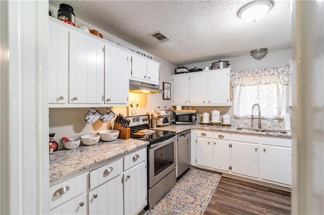 6250 Vivian Broadus Rd, Eight Mile, AL 36613 - kitchen with appliances with stainless steel finishes, under cabinet range hood, dark wood-type flooring, a textured ceiling, and white cabinets