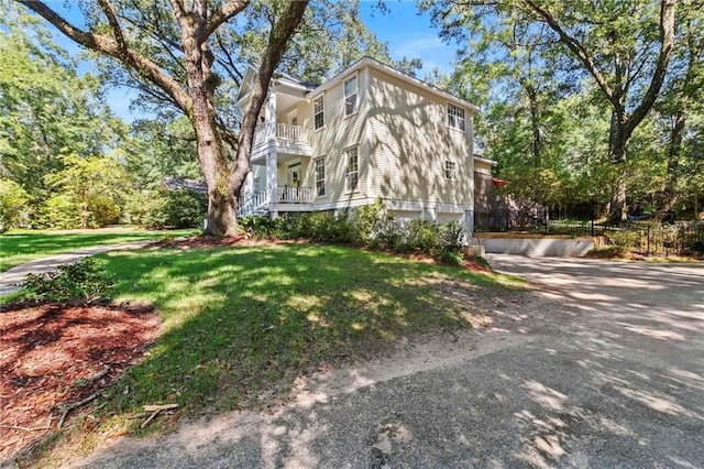 view of home's exterior with a balcony and a lawn