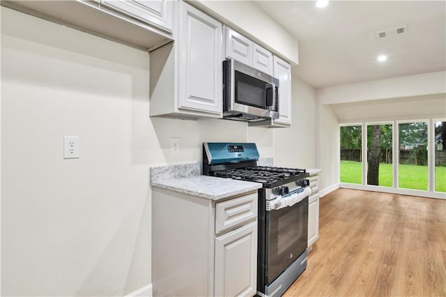 kitchen featuring appliances with stainless steel finishes, baseboards, light wood-style floors, white cabinets, and recessed lighting