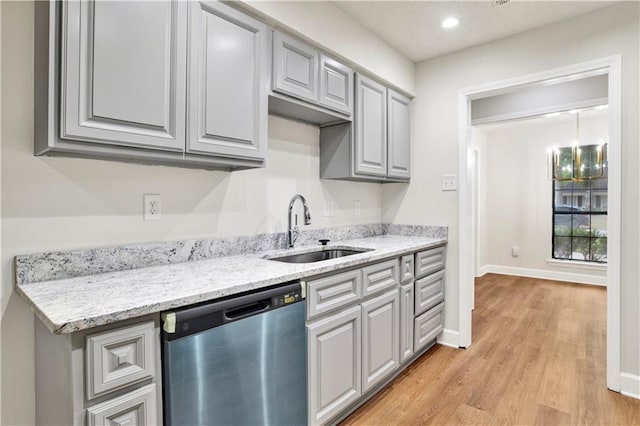 kitchen with dishwasher, a sink, light wood-type flooring, gray cabinetry, and baseboards