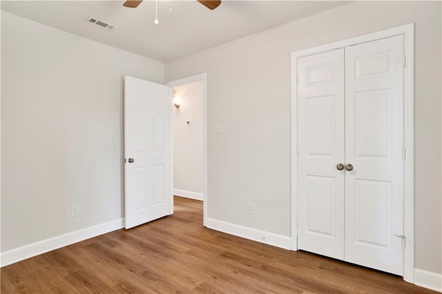 unfurnished bedroom with baseboards, wood finished floors, a closet, and a ceiling fan