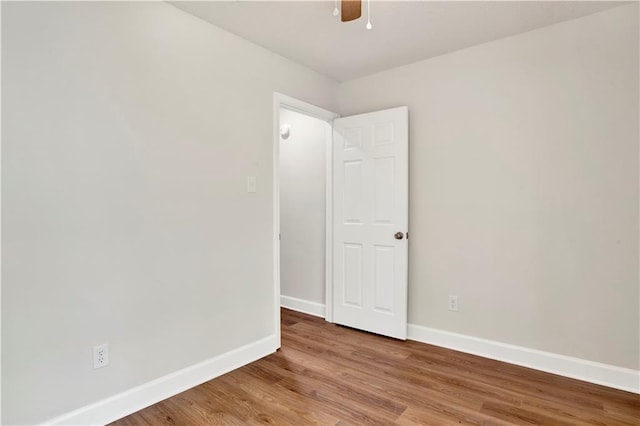 spare room with baseboards, light wood-type flooring, and a ceiling fan