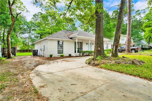 ranch-style home with central AC, brick siding, covered porch, and a shingled roof