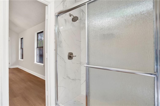 full bathroom with a marble finish shower, wood finished floors, and baseboards