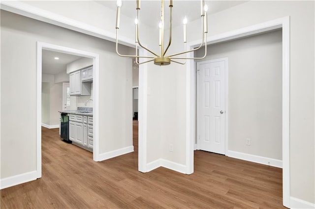 unfurnished dining area featuring a chandelier, wood finished floors, and baseboards
