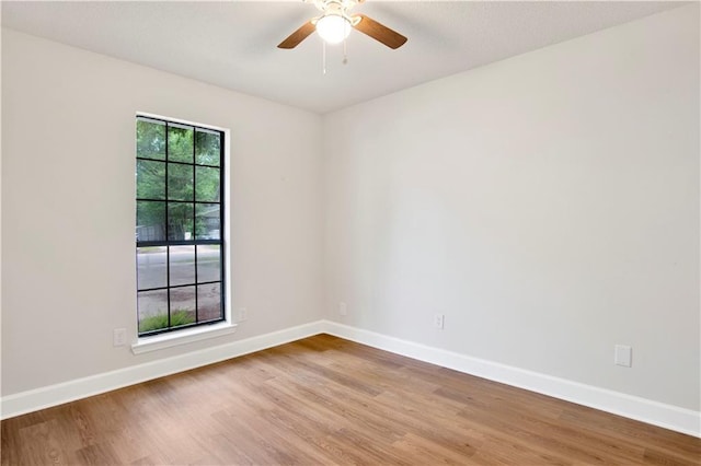 empty room with wood finished floors, baseboards, and a ceiling fan