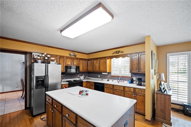 112 Broadmoor Dr, Daphne, AL 36526 - kitchen featuring black appliances, a textured ceiling, light countertops, light wood-style flooring, and a center island