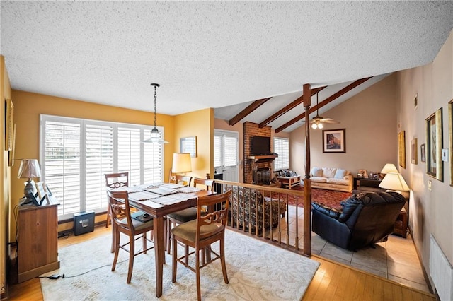 112 Broadmoor Dr, Daphne, AL 36526 - dining room featuring a ceiling fan, light wood-type flooring, a textured ceiling, and a brick fireplace