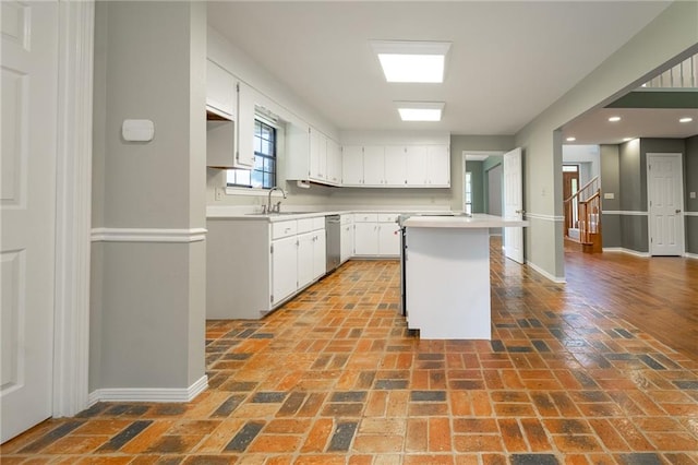 kitchen featuring white cabinets, a center island, dishwasher, and sink