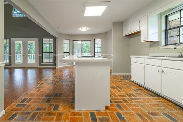 9075 Hamm Cir, Wilmer, AL 36587 - kitchen featuring baseboards, brick flooring, white cabinets, light countertops, and a kitchen island