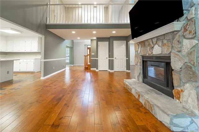 unfurnished living room featuring a fireplace, a towering ceiling, and light hardwood / wood-style floors