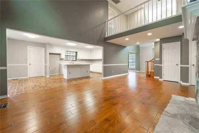 unfurnished living room featuring sink, a high ceiling, and light wood-type flooring