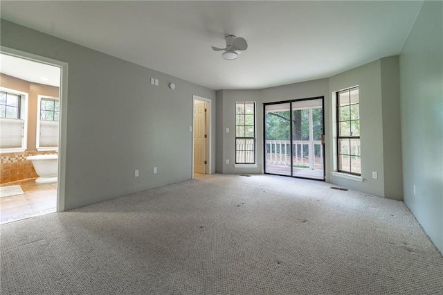 carpeted spare room featuring plenty of natural light and ceiling fan