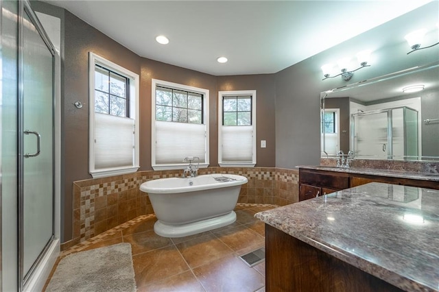 bathroom featuring plus walk in shower, vanity, tile patterned floors, and tile walls