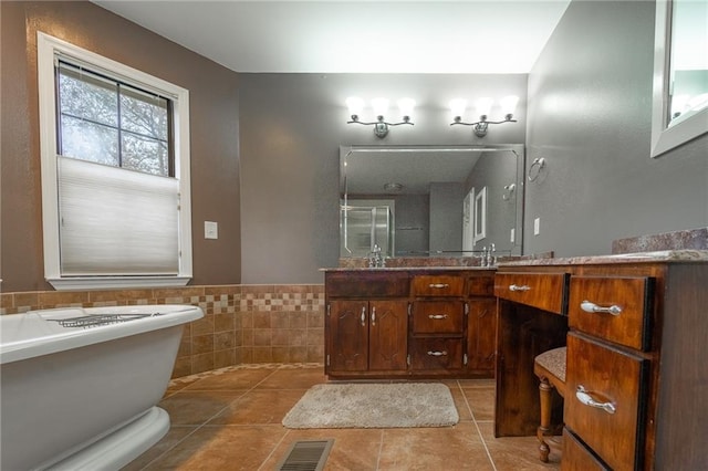 bathroom featuring tile patterned flooring, vanity, tile walls, and a bathing tub