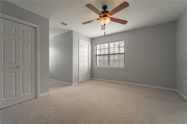 unfurnished bedroom featuring light carpet, ceiling fan, and multiple closets