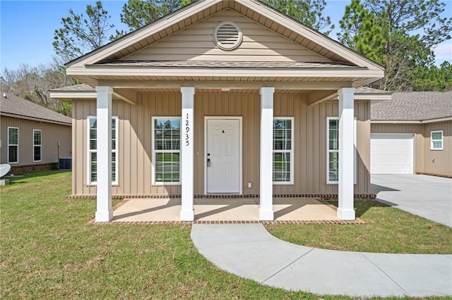 neoclassical / greek revival house featuring a porch, a garage, and a front lawn