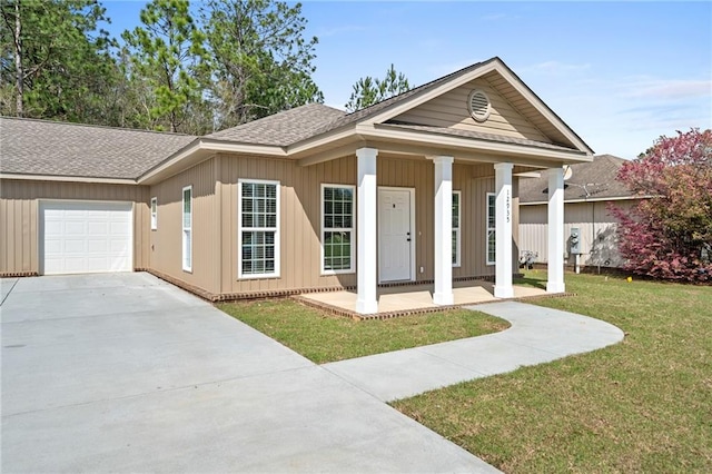 view of front of property with covered porch, a garage, and a front yard